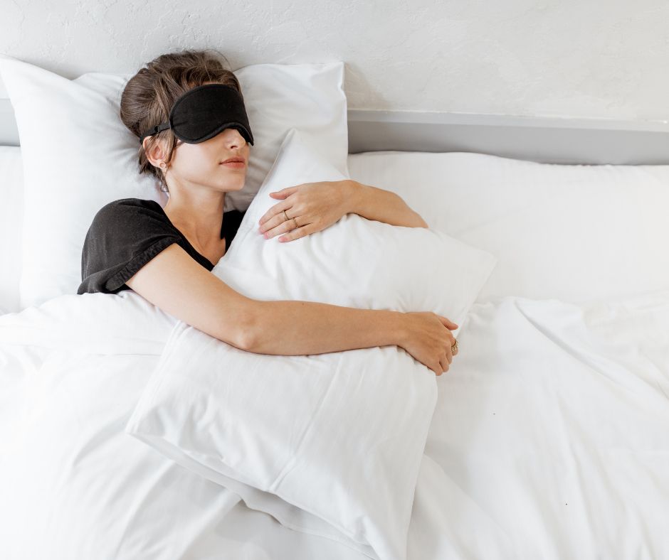 mujer durmiendo en su cama, con sabanas blancas agarrando la almohada